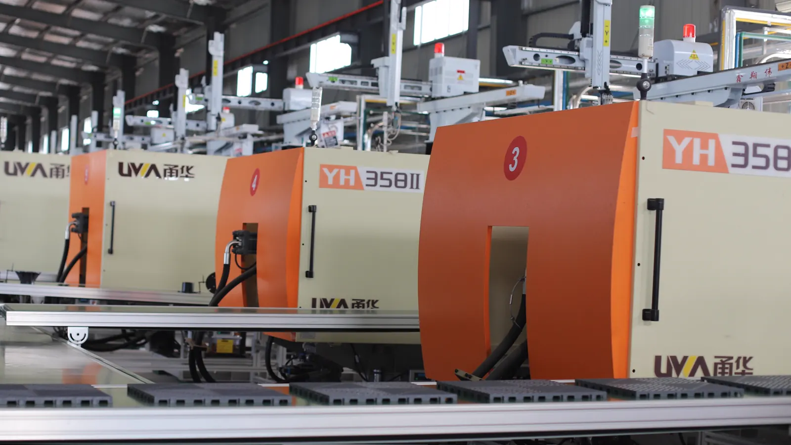 Row of orange and white molding machines on the factory production floor