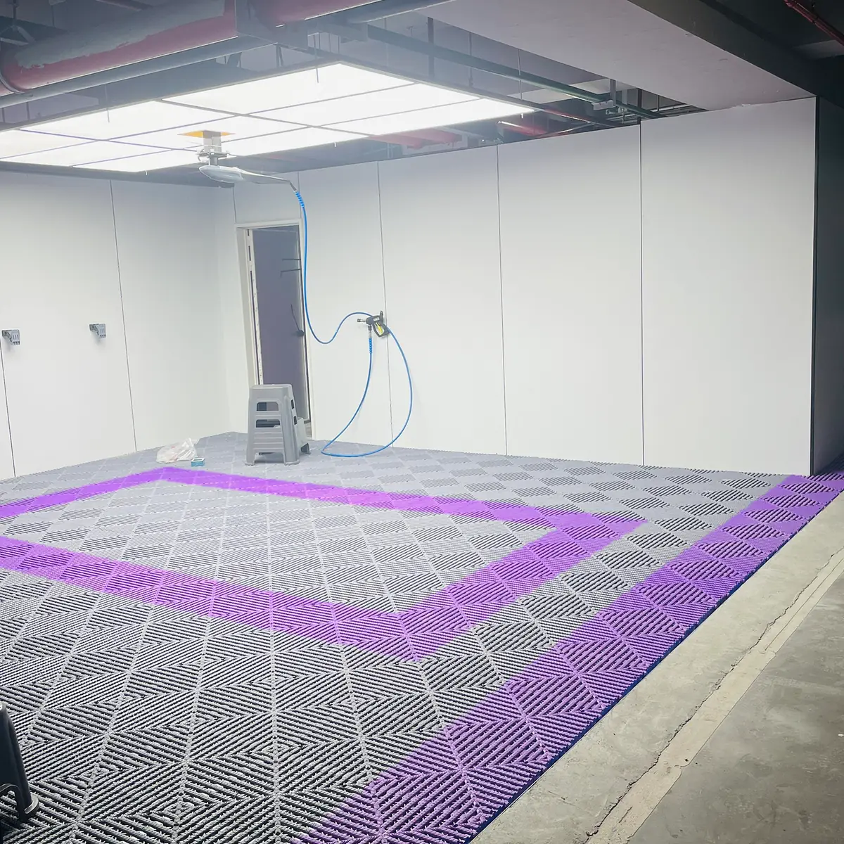 Gray and purple modular garage floor arranged around a vehicle bay