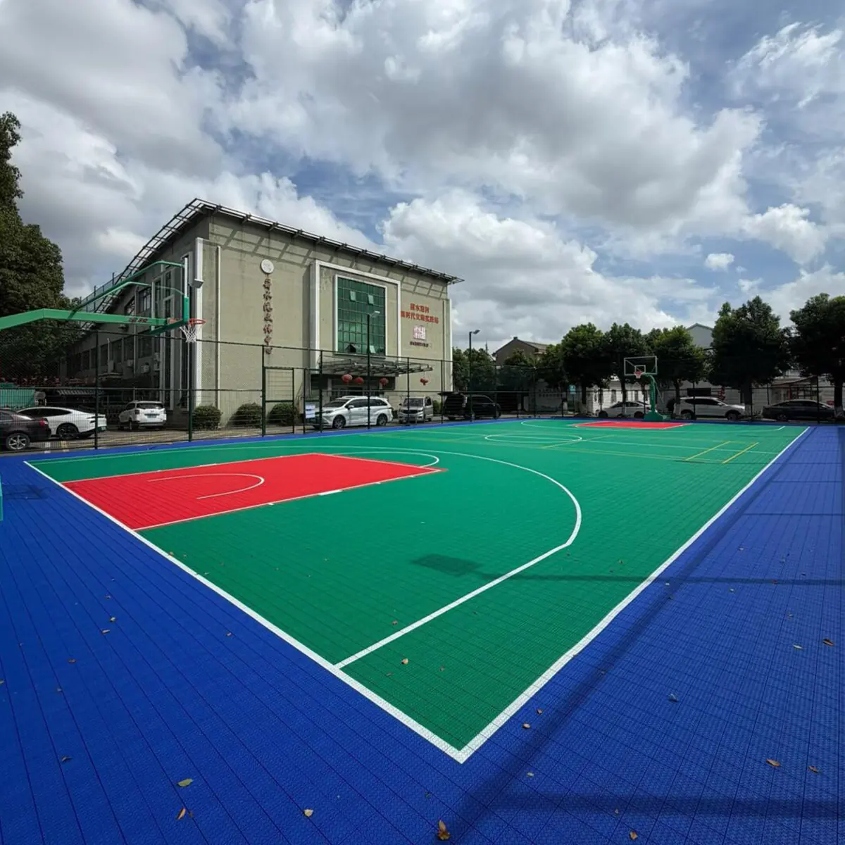 Modular outdoor basketball court viewed across marked zones